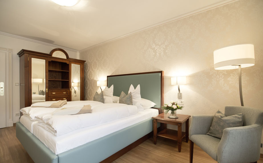 Doppelzimmer mit Sessel und antikem Kleiderschrank