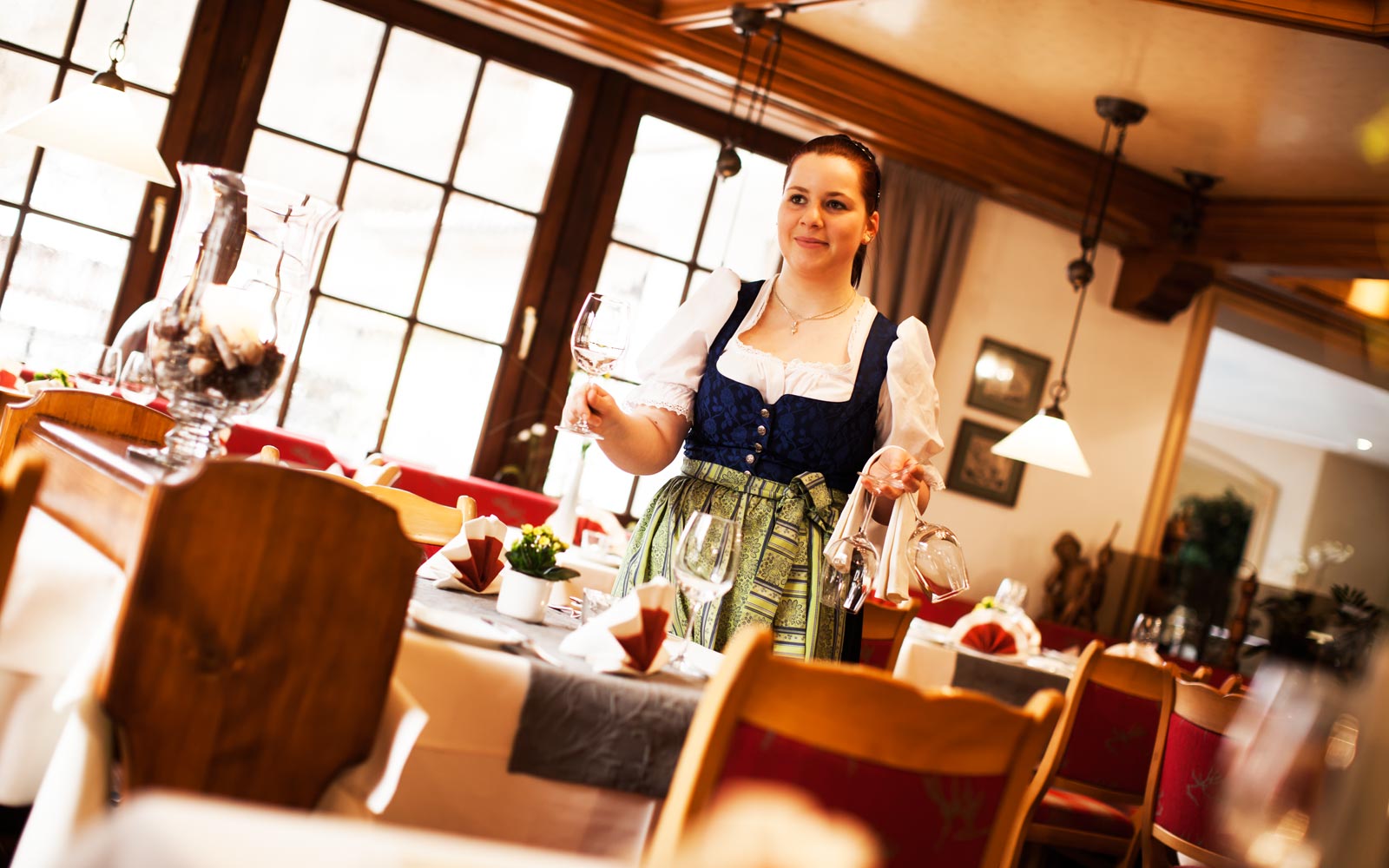 Servicemitarbeiterin im Dirndl serviert Wein im Restaurant