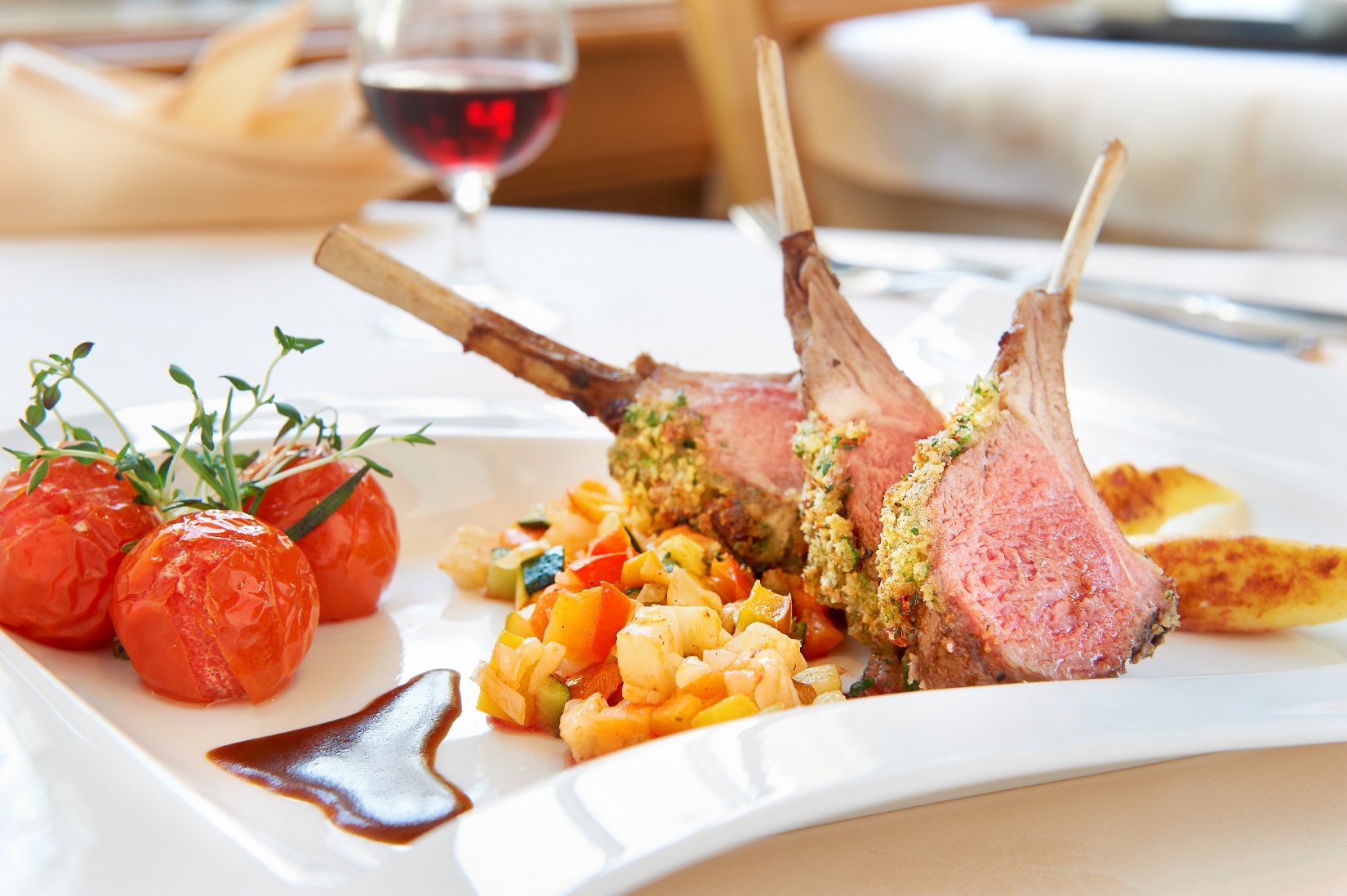 Lammkarree mit Gemüse und gebratenen Tomaten auf Teller