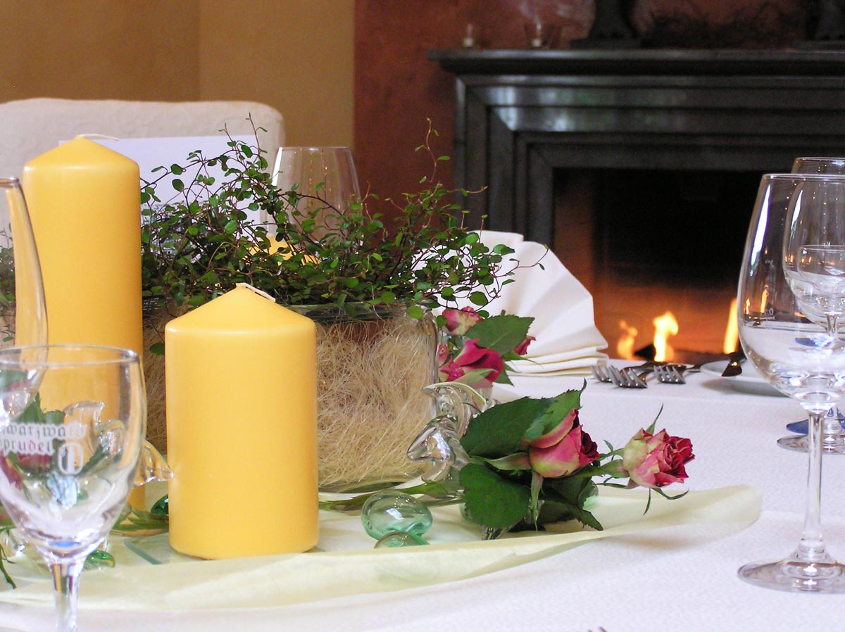Tischdekoration mit Kerzen, Rosen und Kamin im Hintergrund